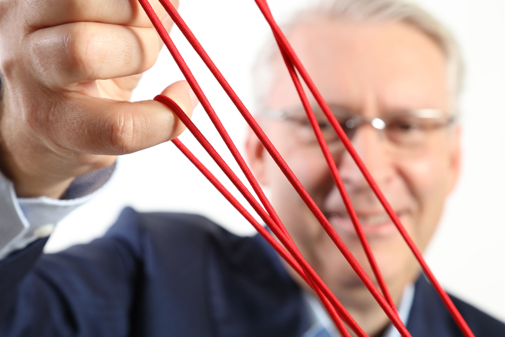 Rote Schnüre vor einem Porträt – das Markenmotiv des Soziators